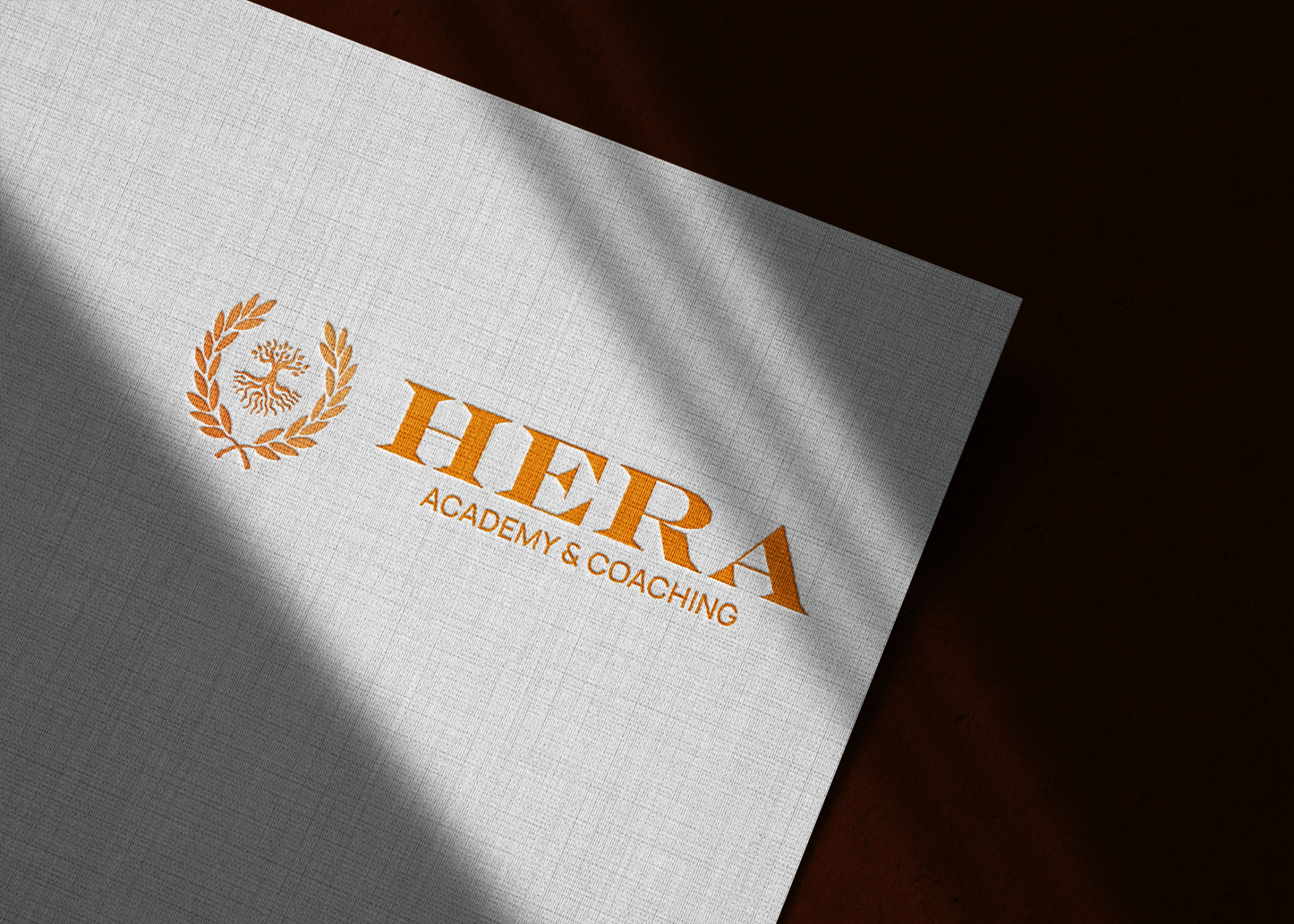 Mockup nhận diện Hera Academy & Coaching trên giấy với logo màu đồng